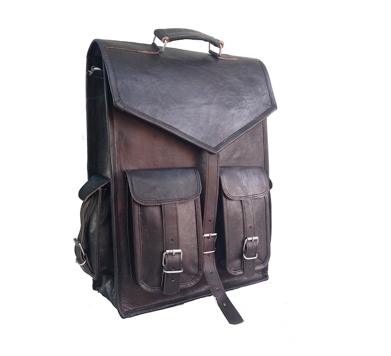 Pode incluir: Uma mochila de couro marrom com dois bolsos grandes na frente e um fecho de aba. A mochila tem uma al&ccedil;a superior e al&ccedil;as ajust&aacute;veis.
