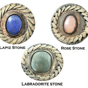 May include: Three round leather and stone embellishments with a braided border. The stones are lapis lazuli, rose quartz, and labradorite.