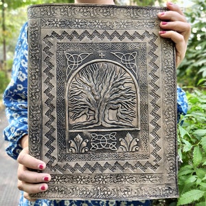 Puede incluir: Un diario de cuero marr&oacute;n con un dise&ntilde;o de &aacute;rbol de la vida en relieve. El diario tiene un borde de nudo celta y detalles intrincados.