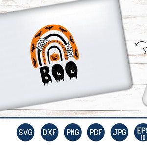 Puede incluir: Un port&aacute;til blanco con una pegatina de Halloween. La pegatina presenta un dise&ntilde;o de arco&iacute;ris con murci&eacute;lagos, telara&ntilde;as y una calabaza. La palabra "BOO" est&aacute; escrita en negro, con un efecto de goteo. Un rat&oacute;n blanco est&aacute; al lado.