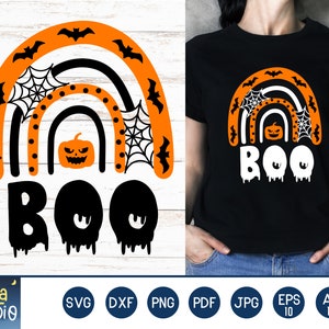 Puede incluir: Camiseta negra con un dise&ntilde;o de arco&iacute;ris de Halloween. El arco&iacute;ris es naranja, negro y blanco, con murci&eacute;lagos, telara&ntilde;as y una calabaza. La palabra "BOO" est&aacute; escrita en blanco con efectos de goteo.