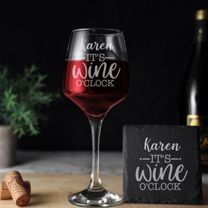 May include: A personalized wine glass and coaster set with the text "Karen - It's Wine O'Clock". The glass is filled with red wine and the coaster is black slate.