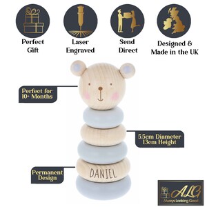 May include: A wooden stacking toy shaped like a bear with a light blue and natural wood colour scheme. The toy has five rings and the bottom ring is personalised with the name "DANIEL". The toy is 5.5cm in diameter and 13cm tall.