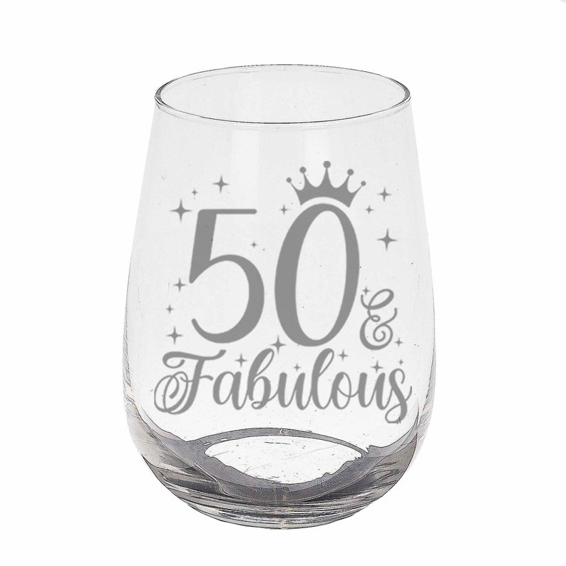 May include: A clear glass wine glass with a silver design that says "50 & Fabulous" with a crown above the 50.