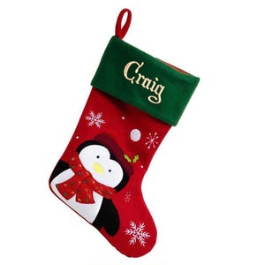 May include: Red and green Christmas stocking with a penguin design and the name "Craig" embroidered on the cuff.