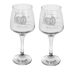 May include: Two clear glass wine glasses with etched designs. The glasses are engraved with the names "Arthur" and "Freya" and the text "30th Anniversary".