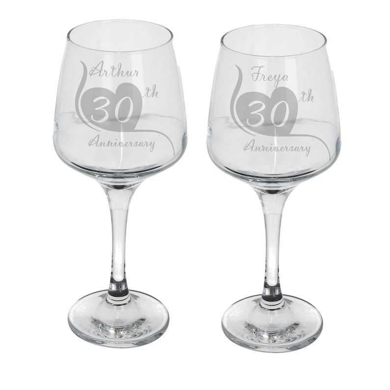 May include: Two clear glass wine glasses with etched designs. The glasses are engraved with the names "Arthur" and "Freya" and the text "30th Anniversary".
