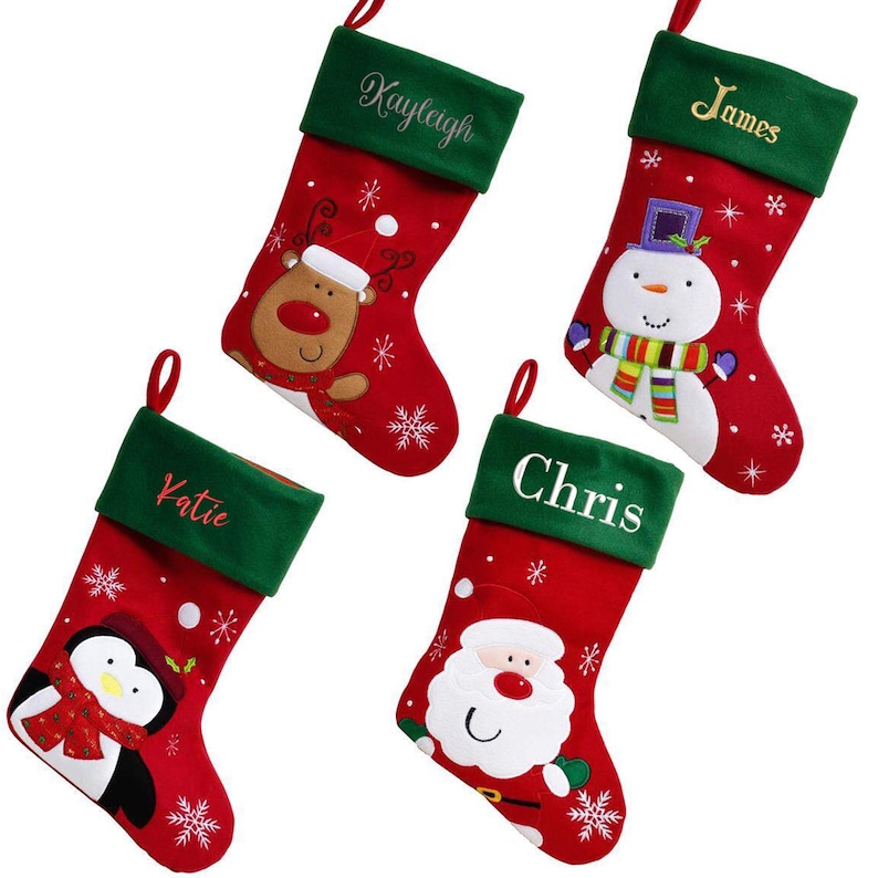 May include: Four red and green Christmas stockings with different embroidered names and festive characters. The stockings feature a reindeer, snowman, penguin, and Santa Claus.
