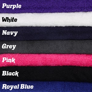 Puede incluir: Una pila de siete toallas de diferentes colores, incluyendo morado, blanco, azul marino, gris, rosa, negro y azul real.