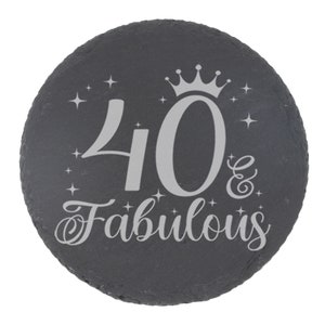 May include: A black slate round coaster with a silver inscription that reads "40 & Fabulous" with a crown above the number 40.