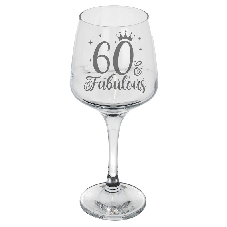 May include: A clear glass wine glass with a gray design that says "60 & Fabulous" with a crown above the number 60.