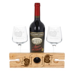 May include: A wooden wine rack with two wine glasses and a bottle of wine. The glasses and rack are engraved with the text "Chris 30th Anniversary" and "Stacey 30th Anniversary".