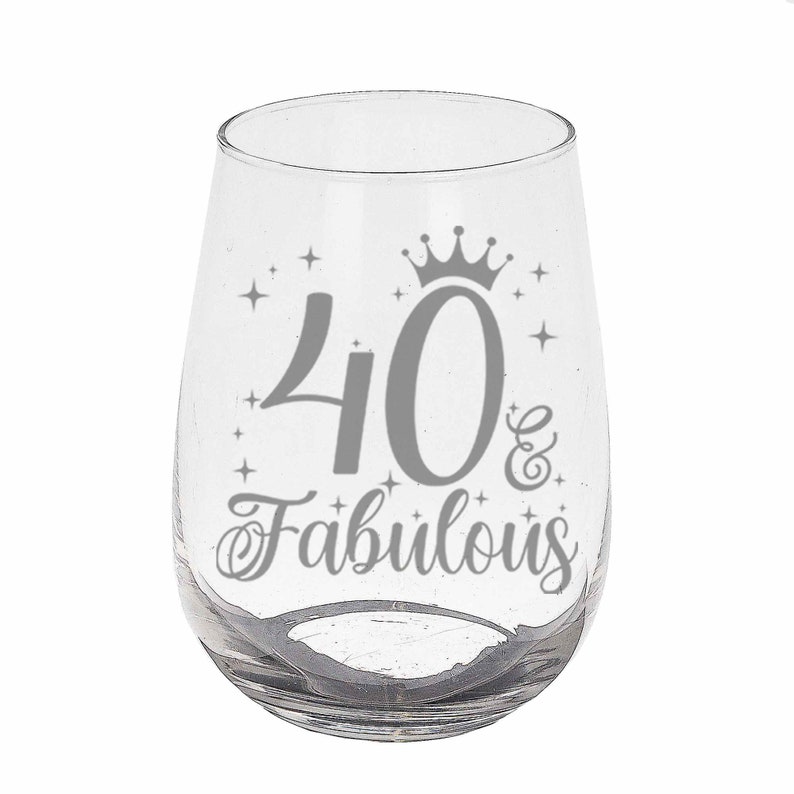 May include: A clear glass wine glass with a silver design that says "40 & Fabulous" with a crown above the number 40.