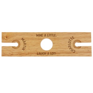 Puede incluir: Portavasos de vino de madera con dos ranuras y el texto "Wine a little, laugh a lot!" con los nombres "Martin" y "Charlotte" grabados en los lados.