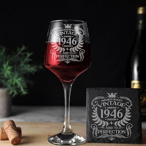 May include: A clear glass wine goblet filled with red wine and a square black slate coaster, both etched with the text: PREMIUM QUALITY VINTAGE LIMITED 1946 EDITION AGED TO PERFECTION, featuring a crown and laurel wreath design.