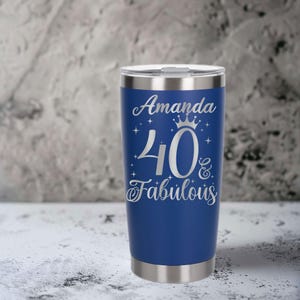 Op de afbeelding: Een blauwe roestvrijstalen tumbler met een zilveren deksel. De tumbler is gegraveerd met de tekst "Amanda 40 & Fabulous" met een kroon boven het getal 40.