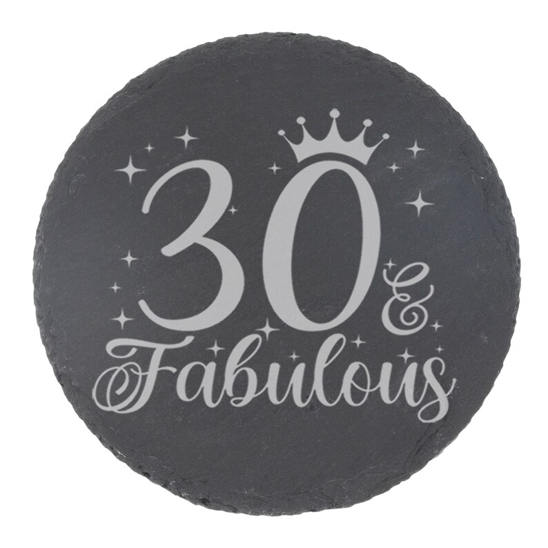 May include: A black slate round coaster with a silver inscription that reads "30 & Fabulous" with a crown above the number 30.