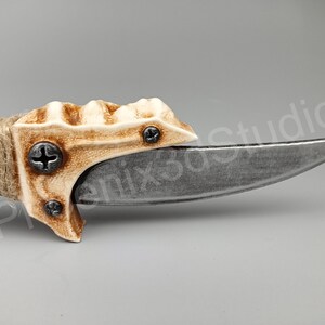 May include: A close-up of a knife with a bone-like handle and a curved blade. The handle is textured and has two screws. The blade is silver and has a sharp point.