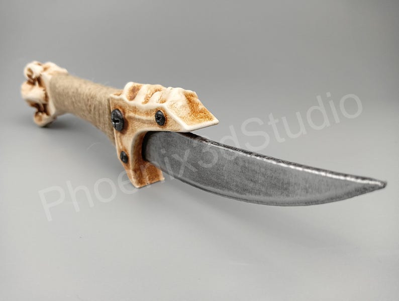 May include: A white and brown bone-handled dagger with a silver blade. The handle is wrapped in twine and has a skull-like design.