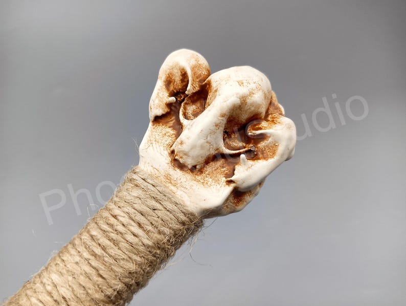 May include: A white ceramic skull with brown accents, wrapped in twine, is a decorative handle for a walking stick.