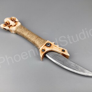 May include: A decorative dagger with a bone-like handle wrapped in twine and a silver blade.