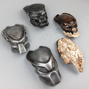 Könnte beinhalten: Fünf Predator-Masken in verschiedenen Stilen und Farben. Die Masken sind aus Kunststoff und haben ein detailliertes Design. Sie sind alle in verschiedenen Farben, darunter Silber, Schwarz, Braun und Weiß.