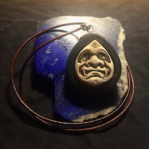 Amulett Hannya-Maske aus Büffelknochen und Ebenholz geschnitzt und mit Silber veredelt.