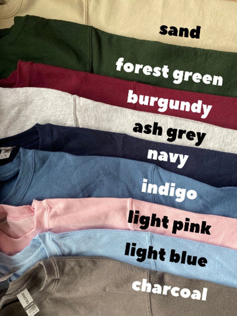 May include: A stack of ten sweatshirts in different colors, including sand, forest green, burgundy, ash grey, navy, indigo, light pink, light blue, and charcoal.