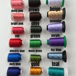 May include: A collection of spools of thread in various colors, including pink, black, white, dusty pink, brown, beige, lavender, bright pink, olive, red, green, purple, electric blue, moss green, icy blue, dark blue, gold, and teal.