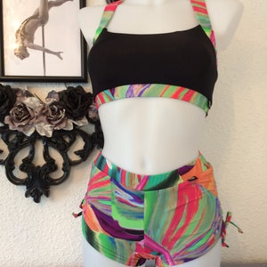 May include: Black sports bra with a colorful abstract print trim and matching high-waisted shorts with a similar print.