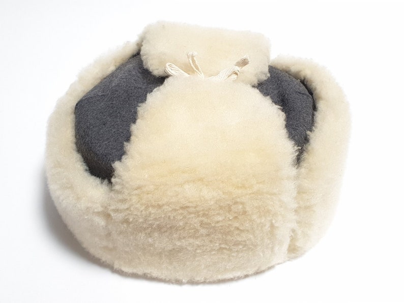 May include: A gray and white winter hat with a thick fur lining. The hat has a drawstring at the top.