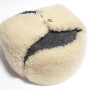 May include: A white and gray fur hat with a fold-over flap and a tie string.