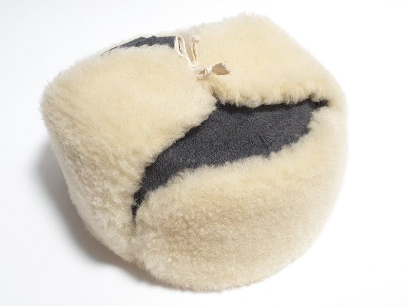 May include: A white and gray fur hat with a fold-over flap and a tie string.