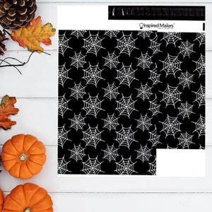 May include: Black and white spiderweb pattern on a mailer. The mailer has a repeating pattern of white spiderwebs on a black background. The words "Inspired Mailers" are visible on the mailer.