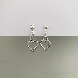 May include: A pair of silver heart-shaped dangle earrings with a small ball at the top of each earring.