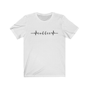 May include: White t-shirt with a black heartbeat graphic that says "coffee" inside the heartbeat.