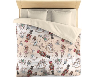 May include: A duvet cover featuring a whimsical Nutcracker theme. The design includes illustrations of ballerinas, mice, nutcrackers, rocking horses, and stars in shades of beige, pink, and gold. The bedding is placed on a bed with beige pillows and a wooden headboard.