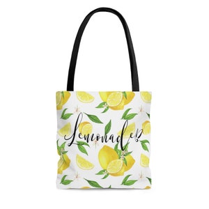 May include: White tote bag with black handles and a lemon print. The bag has the text "Lemonade" written in black cursive.