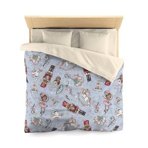 May include: A blue and white duvet cover with a repeating pattern of ballerinas, nutcrackers, mice, and rocking horses. The pattern is in a vintage style with watercolor-like details.