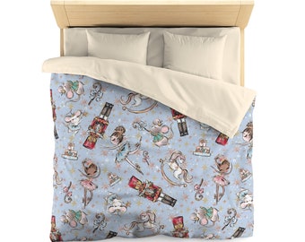 May include: A blue and white duvet cover with a repeating pattern of ballerinas, nutcrackers, mice, and rocking horses. The pattern is in a vintage style with watercolor-like details.
