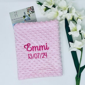 May include: Pink baby blanket with a white polka dot pattern. The blanket is personalized with the name "Emmi" and the date "13/07/24" embroidered in pink.