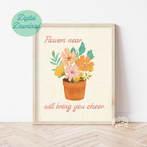 Pode incluir: Uma impressão de arte imprimível com um fundo creme que apresenta uma planta em vaso com flores laranja, rosa e amarelas. O texto "Flowers near will bring you cheer." está impresso em rosa abaixo da planta.