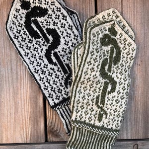 May include: A pair of knitted mittens, one black and white, the other olive green and white. Each mitten features a stylized medical symbol. The mittens are resting on a wooden surface.