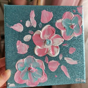 May include: A teal canvas painting with pink, white, and blue flowers. The flowers are painted in a textured style, giving the painting a 3D effect.