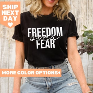 May include: Black t-shirt with white text that reads "FREEDOM over FEAR".