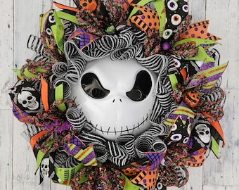 May include: A decorative wreath featuring a central white skull mask with black eyes and a stitched mouth. The wreath is constructed with black and white striped mesh, accented by ribbons in orange, green, and purple, and skull motifs. Happy Door Wreaths.