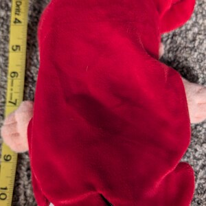 May include: A plush doll featuring a red velvet hair and a green sequined tail. The doll's hair is styled to the side. The doll is approximately 6 inches tall.