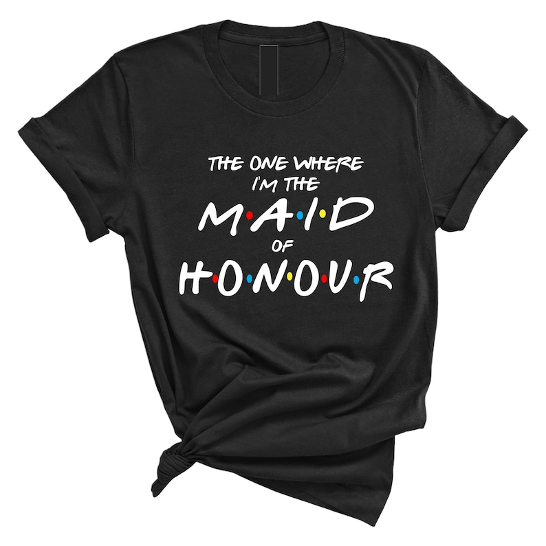 May include: Black t-shirt with white text that reads "The One Where I'm The Maid Of Honour" in a font reminiscent of the show Friends. The text has colorful dots around it.