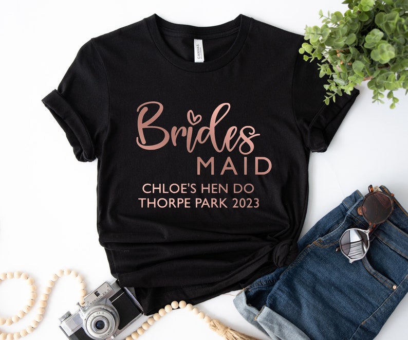 May include: Black t-shirt with rose gold text that reads "Brides Maid Chloe's Hen Do Thorpe Park 2023".