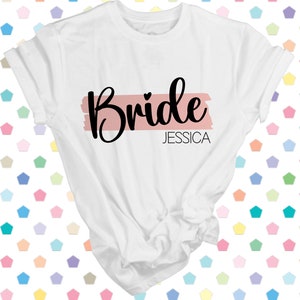 May include: White t-shirt with the word "Bride" in black script with a pink stripe and the name "Jessica" underneath.
